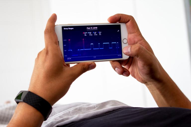 Man laying  monitoring his sleep night with app.